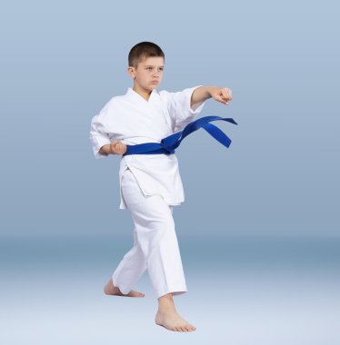 Mavi bir kemerle karate atlet yumruk kol atıyor.