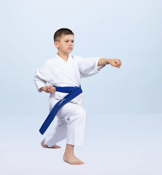 Boy in karategi beats punch arm on a light background — Stock Photo, Image