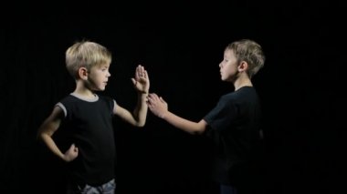 Siyah tişörtlü iki sporcu siyah arka planda eşleşen egzersizler yapıyor.