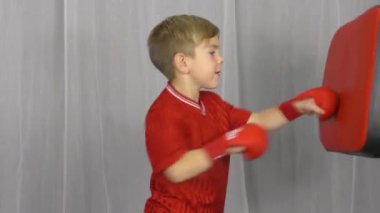 Kolları kırmızı kaplamalı küçük bir atlet simülatörü yumrukluyor.