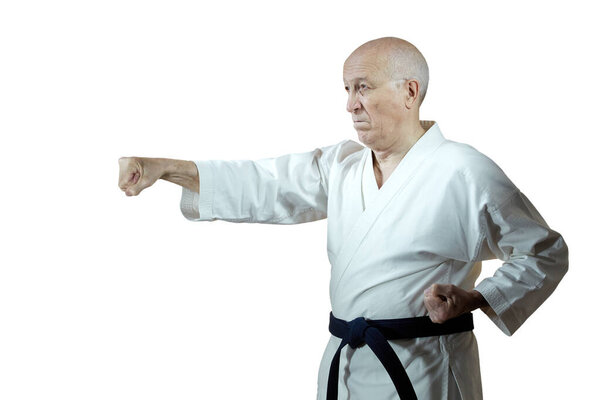 On white isolated background old man athlete in karategi beats hand punch