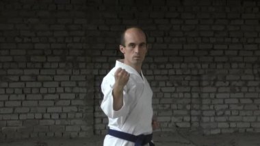 Tuğla duvarın arkasında, yetişkin bir sporcu elleriyle yumruk ve blok yapar.