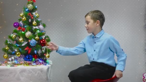 Kleiner Junge Dreht Sich Auf Einem Stuhl Neben Dem Weihnachtsbaum — Stockvideo