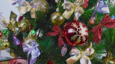 Hafif bir arka planda, küçük bir Noel ağacı büyük bir Noel ağacının yanında duruyor.
