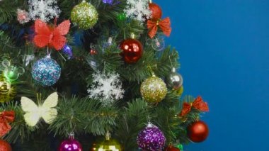Çok renkli süslemeleri ve mavi arka planda ampulleri olan dekore edilmiş Noel ağacı.