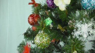 Gerdanlık ve oyuncaklarla süslenmiş bir Noel ağacı hafif bir arka planda dönüyor