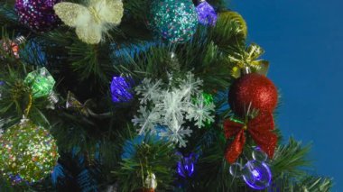 Mavi arka planda, yanıp sönen bir çelenk ve renkli oyuncaklar Noel ağacında