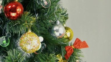 Işıklı arka planda, yanıp sönen ışıklar ve yeşil bir Noel ağacında renkli oyuncaklar.