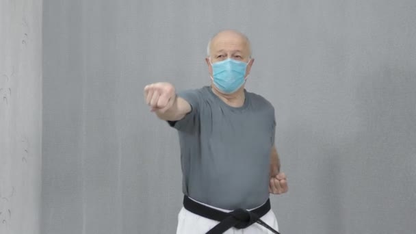 一个戴着黑带的医疗面罩的老男子运动员正在训练轮滑和拳击 — 图库视频影像