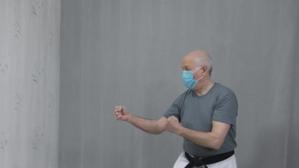 一个戴着黑带的医疗面具的老运动员在训练中踢腿 — 图库视频影像