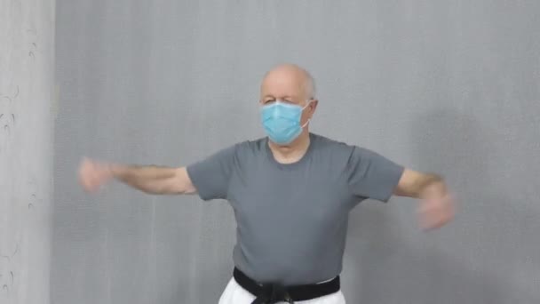 Медицинской Маске Черным Поясом Старик Спортсмен Тренирует Вращение Рук Прыжке — стоковое видео