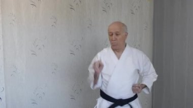 Beyaz katategi 'de, yaşlı bir atlet elleriyle yumruk ve blok yapar.