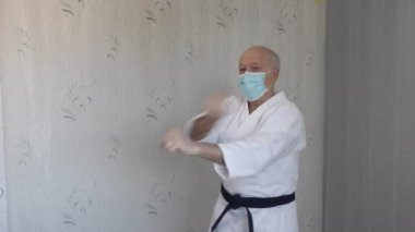 Tıbbi maskeli yaşlı sporcu ve beyaz katategi trenleri elleriyle blokları dolduruyor.