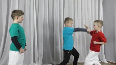 Çok renkli tişörtler giyen üç sporcu birbirlerini görmek için blok ve tekme atıyorlar.
