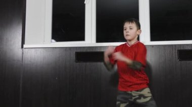 Kırmızı tişörtlü bir sporcu yerinde koşuyor ve yumruk atıyor.