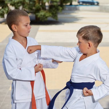 İki sporcu açık havada yumruk ve savunma teknikleri deniyor.