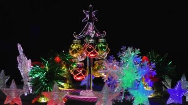 Noel kartı. Kar taneleri, çanlar ve yıldızların arasında küçük bir Noel ağacı.