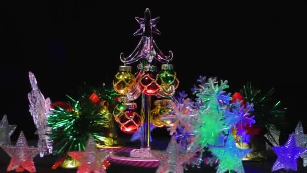 在雪花 铃铛和有背光的星星之间的一棵小小的圣诞树上挂着圣诞贺卡 — 图库视频影像
