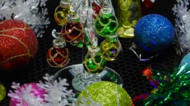 Yeni yıl kartı etrafında kar taneleri çanları ve toplarla çevrili küçük bir Noel ağacı hareket halinde.