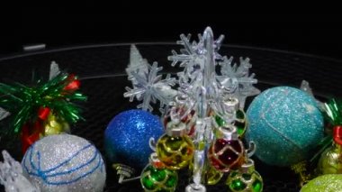 Yeni yıl kartı etrafında kar taneleri çanları ve toplarla çevrili küçük bir Noel ağacı hareket halinde.