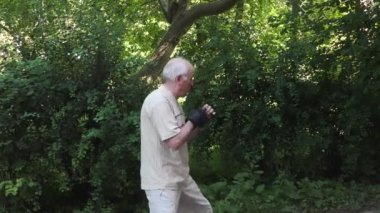 Siyah eldivenli yaşlı atlet art arda birkaç yumruk antrenmanı yapıyor.