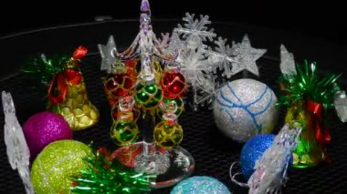 Etrafında kar taneleri, çanlar ve toplar, hareket halindeki küçük bir Noel ağacı