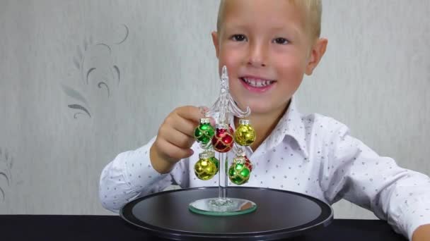 Vrolijk Kind Raakt Speelgoed Aan Een Draaiende Kerstboom — Stockvideo