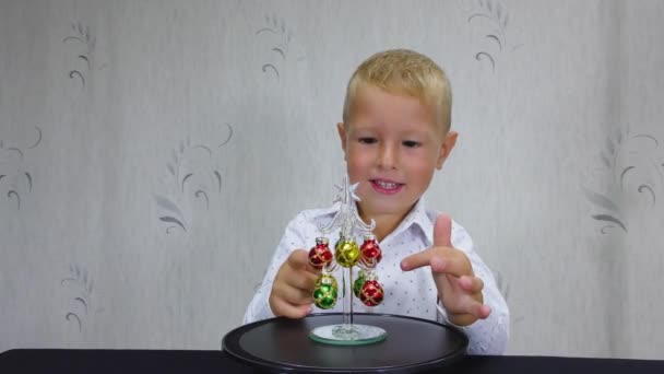 Uma Criança Camisa Branca Assiste Uma Pequena Árvore Natal — Vídeo de Stock