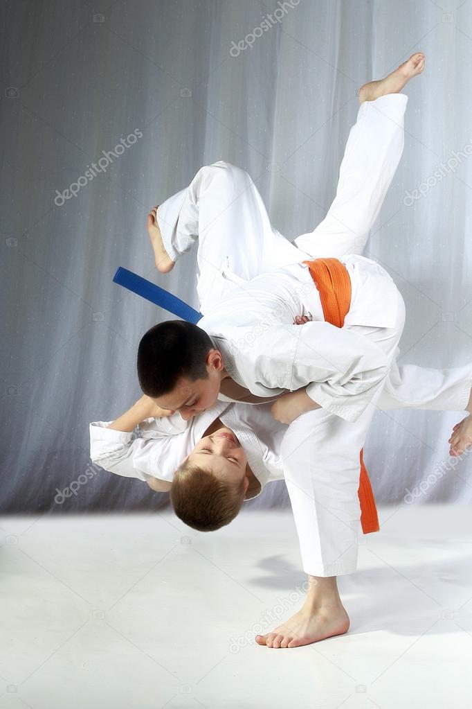 Young athlete with an orange belt performs technique nage-waza