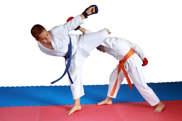 Los chicos están entrenando golpes de karate en la alfombra roja y azul — Foto de Stock