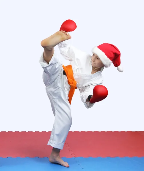 Sportswoman in hat Santa Claus is doing circular kick leg — Stock Photo, Image