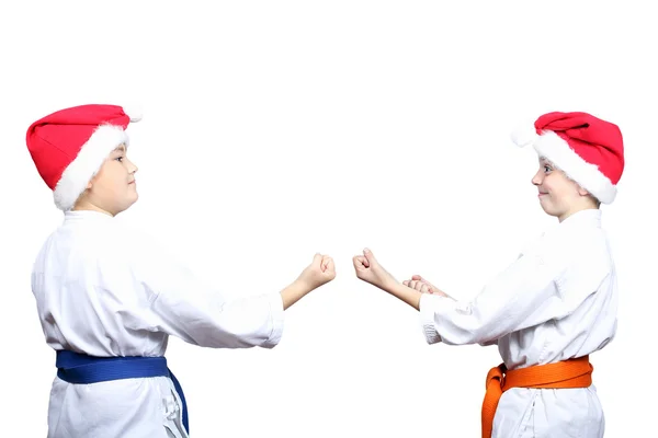 Em um fundo branco pequenos atletas em bonés de Papai Noel estão de pé em rack de karatê — Fotografia de Stock