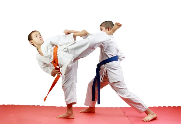 On a red mats sportsmen are training paired exercises karate — Stock Photo, Image