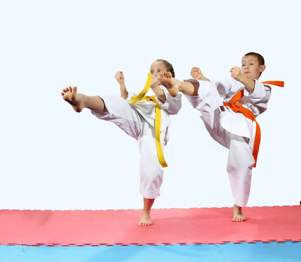 Girl and boy in karategi are beating kick leg forward — Stock Photo, Image