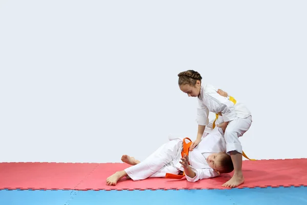 En la alfombra roja y azul chico y chica en karategi están entrenando lanzando — Foto de Stock