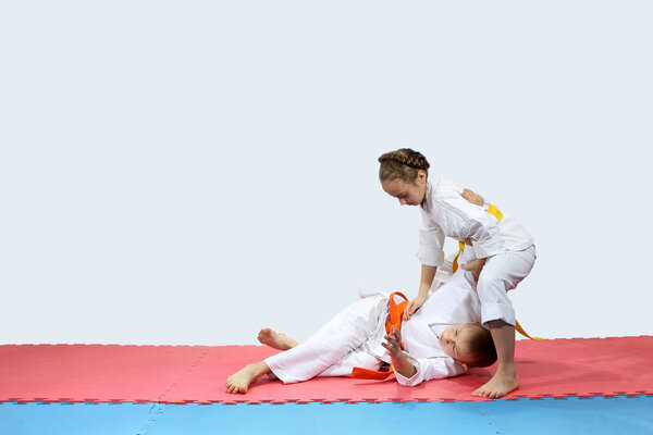 On the red and blue mat boy and girl in karategi are training throwing