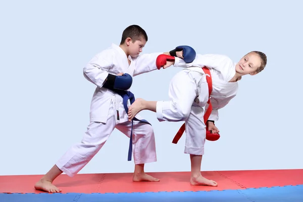 On the red and blue mats athletes  are doing paired exercises karate — Stock Photo, Image