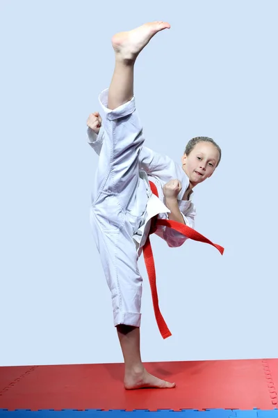 On a light background sportswoman is doing roundhouse kick — Stock Photo, Image