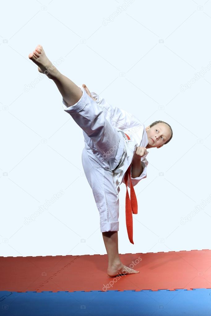 Sportswoman with a red belt beats roundhouse kick leg