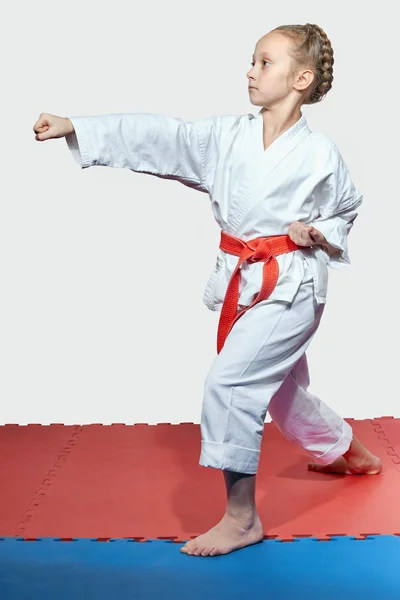 Girl with red belt in the rack of karate is beating blow arm — Stock Photo, Image