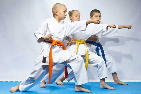 Three sportsmen are beating blows arms on a blue mats — Stock Photo, Image