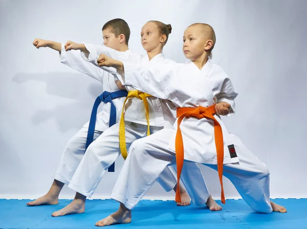 Twee jongens en een meisje in karategi raken punch arm — Stockfoto