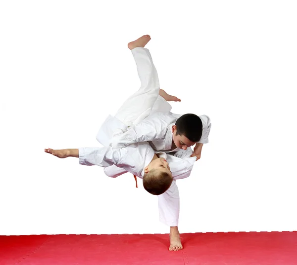 En una alfombra roja atletas están entrenando judo lanza — Foto de Stock