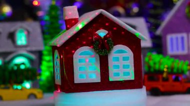 Kırmızı küçük bir ev bir Noel kasabasının arka planında dönüyor.