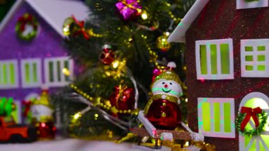 Kırmızı küçük bir ev bir Noel köyünün arka planında dönüyor.