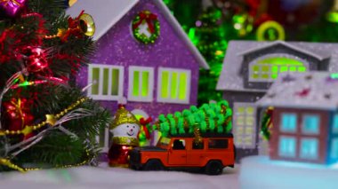 Üç renkli bir ev bir Noel köyünün arka planında dönüyor.