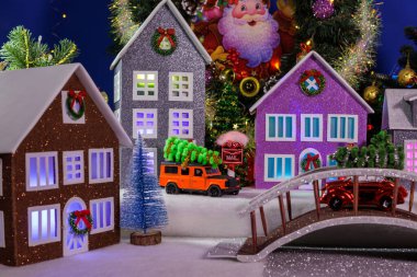 Aydınlatılmış pencereleri ve merkezinde köprüsü olan çok güzel renkli evleri olan bir Noel köyü.