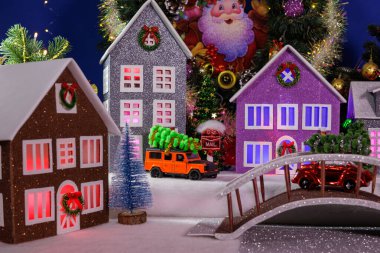 Aydınlatılmış pencereleri ve merkezinde bir köprüsü olan çok renkli güzel evleri olan bir Noel kasabası.