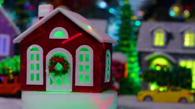 Köyün merkezinde küçük, parlak, kırmızı bir Noel evi dönüyor.