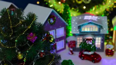 Büyük bir ağacı olan bir Noel kasabasının önünde dönen gri bir evin yakın çekimi.